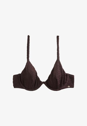 Soutien-gorge en tissu marron foncé texturé avec fines bretelles réglables et armatures, présentant un petit logo métallique de la marque sur le côté de la bande.