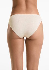 Svetlobéžové bavlnené nohavičky s hladkou textúrou, stredne vysokým pásom a minimálnymi švami, zobrazené zozadu.