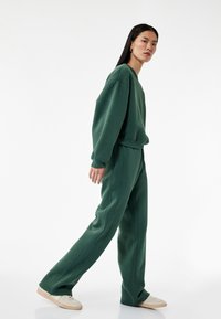 Grøn, oversized sweatshirt og matchende sweatpants i blødt stof, med afslappet pasform, rund halsudskæring og synlige syninger.