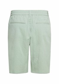 Light green shorts with textured fabric, elastic waistband, and two back pockets. Casual design, knee-length fit, subtle pattern visible.