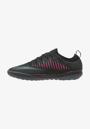 Chaussure de sport noire avec des bandes diagonales roses, semelle texturée avec des taches roses et tirette au talon, vue de profil.