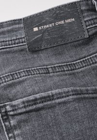 Grijze denim jeans met een leren label met de tekst "STREET ONE MEN," met stiksels en een gladde stoftextuur.