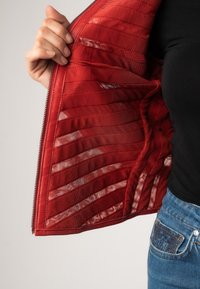 Rode jackinterieur met een horizontaal gestikt patroon, lichtgewicht stof en een soepele textuur met een rits langs de rand.