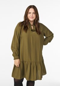 Õlivärvi roheline pika varrukaga kleit kobarate alläärega, millel on võtmeaugukaelus satside ja kurrutatud mansettidega. Sile, kerge kangas.