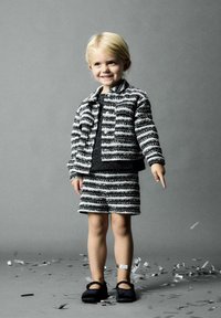Completo per bambini con giacca a righe bianche e nere e pantaloni corti coordinati. Il tessuto ha una finitura texturizzata. Scarpe nere completano il look.