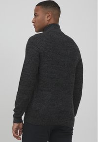 Dunkelgrauer Strickpullover mit hohem Kragen, gerippten Manschetten und Saum. Verfügt über ein strukturiertes Muster und eine entspannte Passform.