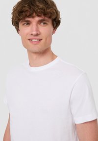 Vit bomullströja med klassisk rund halsringning och korta ärmar, med en slät textur och enkel design. Lämplig för avslappnad användning.