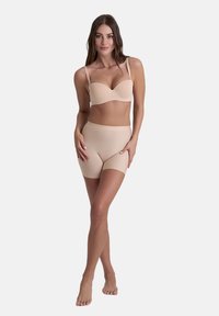 Beige sömlös bh med byglar, mjuka kupor och justerbara band, kombinerad med matchande högmidjade boyshorts i ett slätt tyg.
