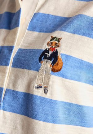 Kék és fehér csíkos pamut pólóing, amelyen egy hímzett róka figura látható, aki sötétkék kabátot, fehér nadrágot és cipőt visel.