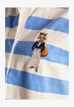 Kék és fehér csíkos pamut pólóing, amelyen egy hímzett róka figura látható, aki sötétkék kabátot, fehér nadrágot és cipőt visel.