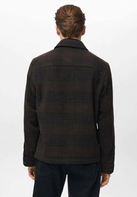 Chaqueta de cuadros marrón hecha de tela texturizada, con un cuello clásico y puños abotonados. La parte trasera presenta un acabado limpio con costuras en los hombros.