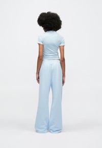 Világoskék pamut rövid ujjú póló világoskék, laza szabású melegítőnadrággal, elasztikus derékpánttal és puha textúrával.