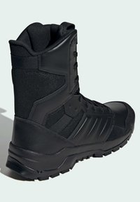 Black tactical boot with a textured synthetic upper, padded collar, round laces, and a rugged rubber sole featuring deep treads.