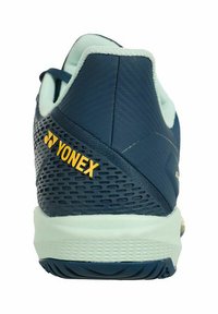 Scarpa sportiva Yonex con una toma blu navy e dettagli in rete, accenti azzurri e una suola texture. Logo giallo sul tallone.