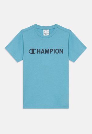 En lys blå bomull t-skjorte med korte ermer og rund hals. Har et stort svart "CHAMPION"-logo over fronten. Enkelt design.