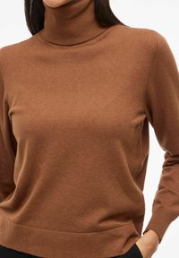 Brązowy sweter z golfem wykonany z miękkiego, teksturowanego materiału, z długimi rękawami i żeberkowymi mankietami. Prosty fason z dopasowaną sylwetką.