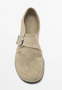 Beige suede shoe with a rounded toe and a single silver buckle across the upper strap. Features minimal stitching and a smooth inner lining.
