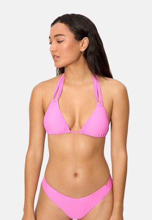 Mujer con cabello largo y oscuro, vistiendo un bikini rosa de cuello halter, mirando hacia su izquierda sobre un fondo liso.