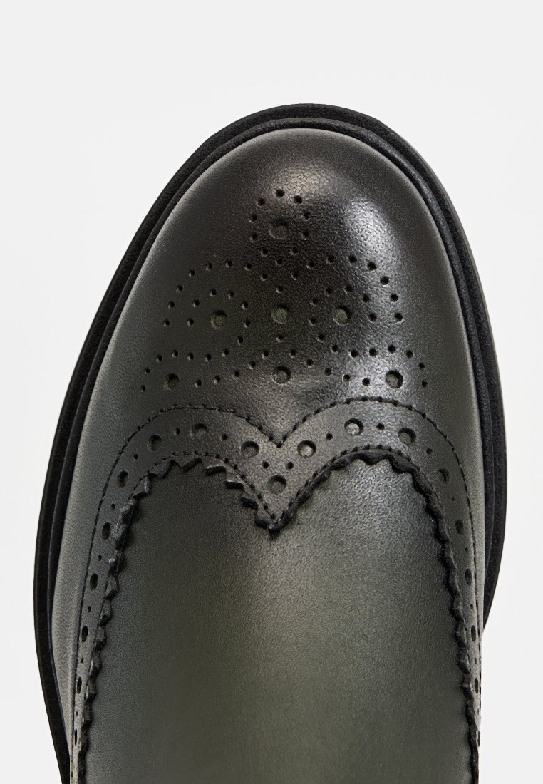 Zwarte leren schoen met een brogue ontwerp, voorzien van geperforeerde details en een gegolfde rand, een gladde afwerking en een ronde teenvorm.