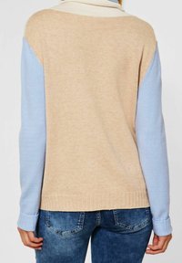 Stickad tröja med en färgblockdesign i beige, ljusblå och gräddfärgade sektioner. Ribbat avslut på ärmar och nederkant, mjuk textur.