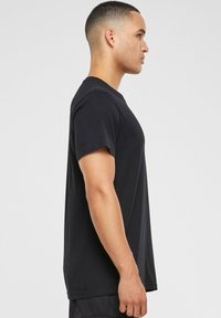 Sort bomulds t-shirt med korte ærmer og rund halsudskæring, vist fra siden, med en glat tekstur og lige snit.