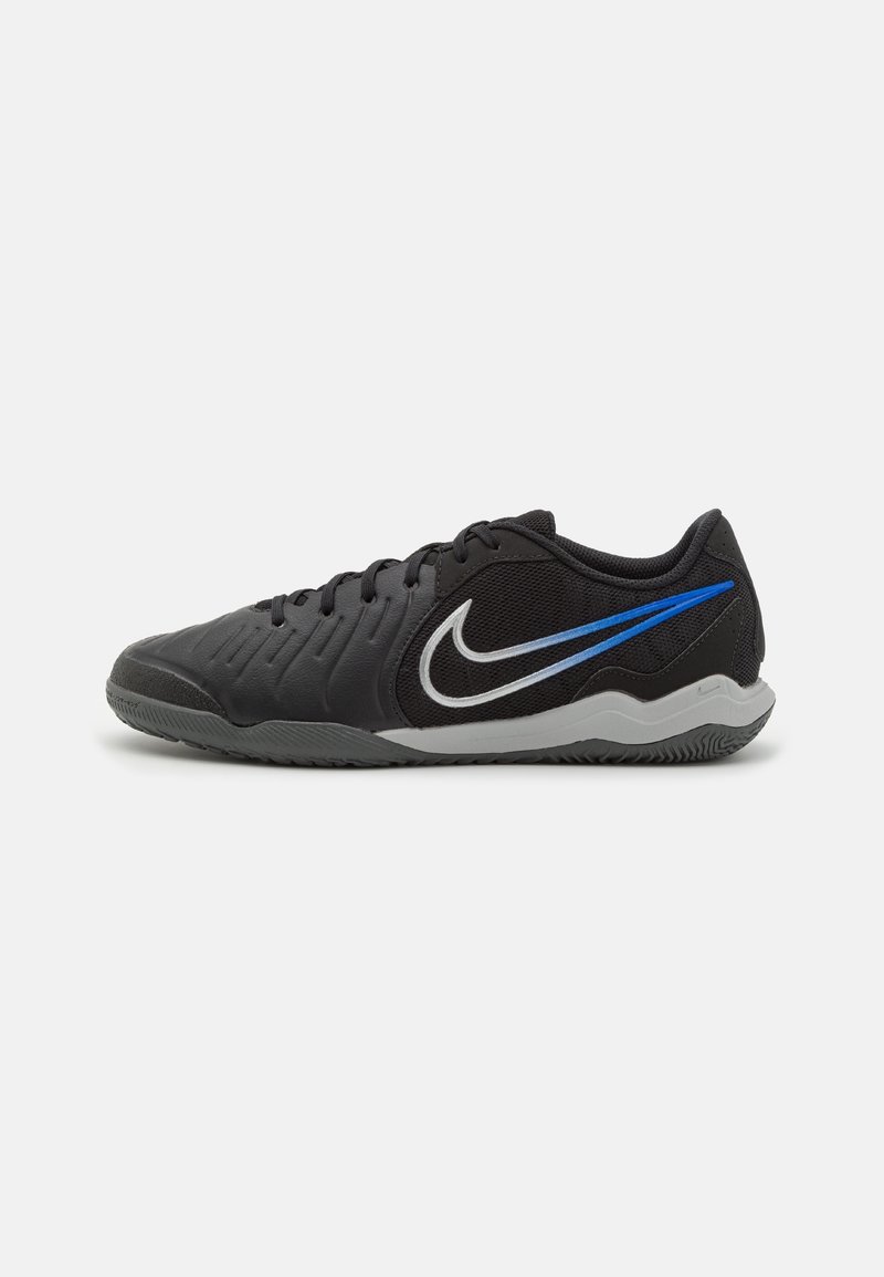Baskets Nike noires à coupe basse avec semelle grise, logo swoosh bleu et blanc, et tige en mesh noir sur fond blanc.