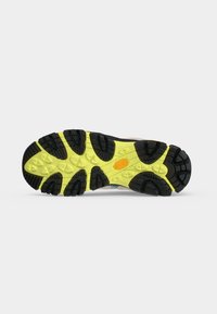 Semelle d’une chaussure avec un profil noir et jaune, des rainures profondes et un logo Vibram orange dans la zone de la voûte plantaire.