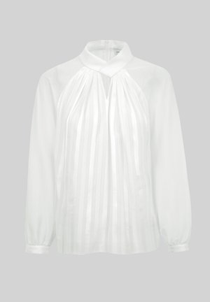 Biała bluzka z długim rękawem, z wysokim dekoltem, pionowymi przezroczystymi paskami z przodu, z wycięciem typu keyhole oraz mankietami zapinanymi na guziki na jednolitym tle.