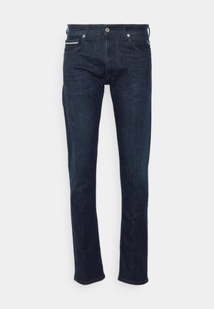 Dark blue denim jeans with a straight fit, featuring front pockets and a metal button closure. The fabric has a smooth texture.