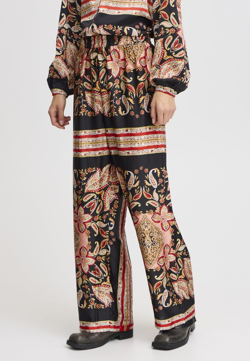 Zwarte wijde broek met een kleurrijk bloemen- en paisleypatroon, een elastische tailleband en contrasterende rode en gouden accenten aan de zomen.
