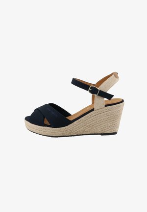Wedge sandals with a navy textile upper, peep-toe design, and woven jute platform. Features adjustable strap with a metal buckle.