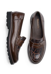Paire de mocassins en cuir marron brillant avec semelles noires robustes, présentant un motif animal texturé à l'avant et une bride sur le dessus.