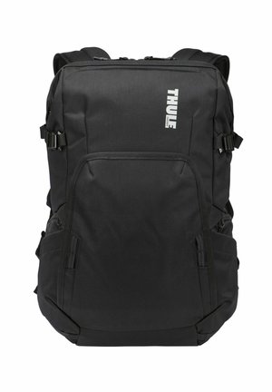 Sac à dos noir Thule avec plusieurs compartiments zippés et sangles latérales réglables, conçu pour un usage quotidien durable.