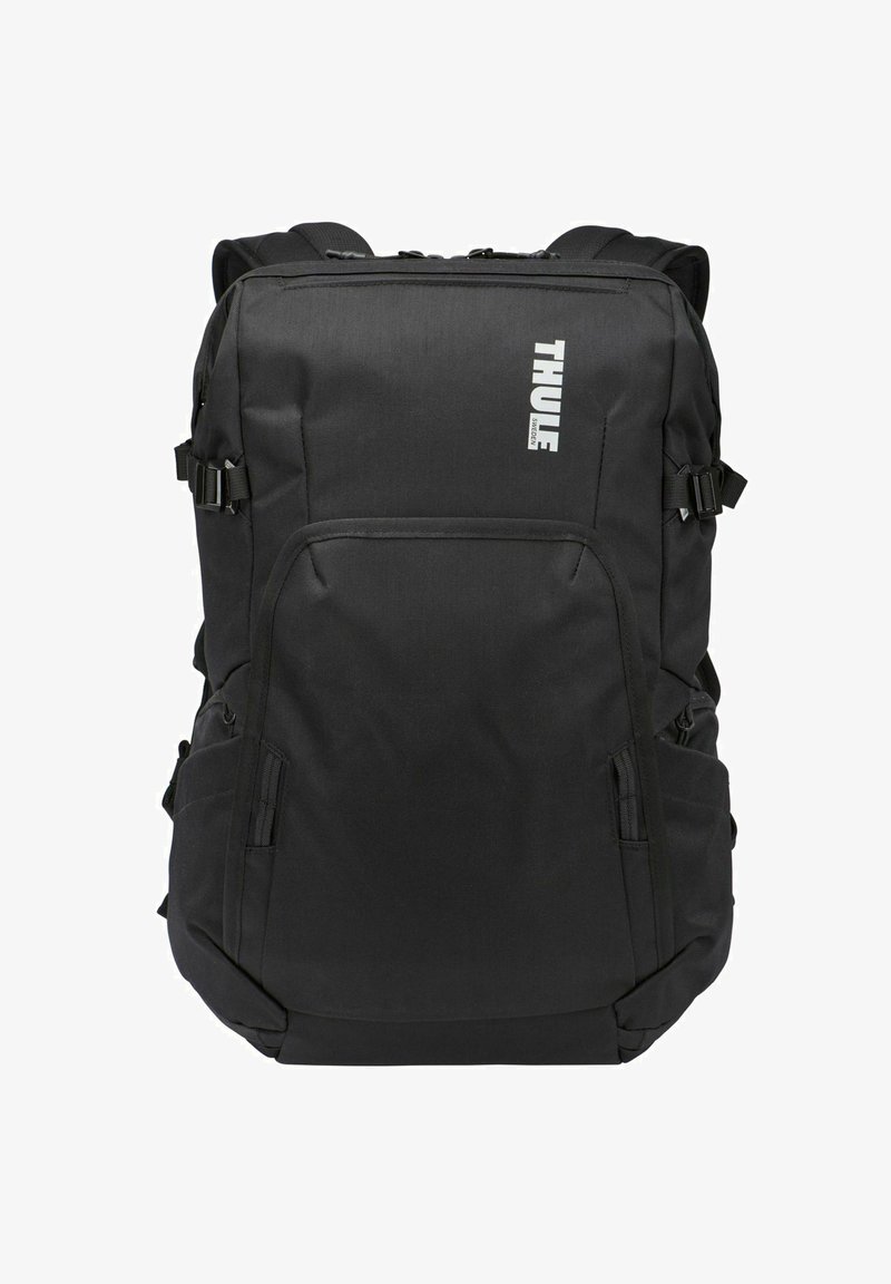 Sac à dos noir Thule avec plusieurs compartiments zippés et sangles latérales réglables, conçu pour un usage quotidien durable.