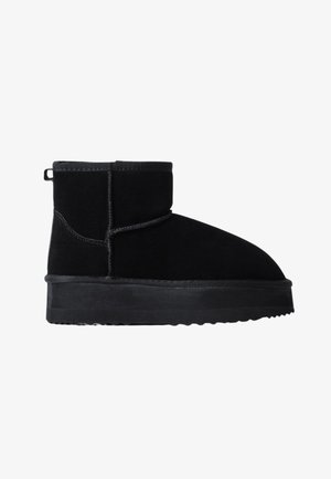 Stivaletti in suede nero alla caviglia con punta arrotondata, suola in gomma piatta e tassello di rinforzo sul tallone, caratterizzati da cuciture sottili e una texture liscia.