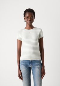 Lichtgroene gestreepte t-shirt met een ribbelstructuur en korte mouwen, met een klein logo op de borst. Gecombineerd met blauwe jeans.