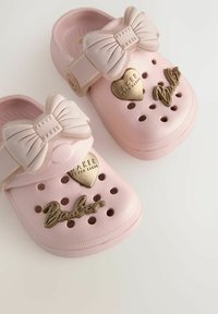 Roosa kummist sabad, millel on dekoratiivne sall, südamekujulised aktsendid ja sõna "Baker" kuldsetes tähtedes. Kujundatud ventilatsiooniavadega.