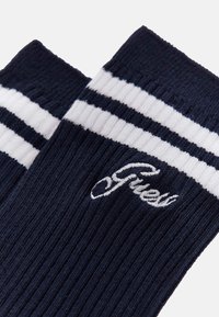 Calzini blu navy con coste verticali, con due strisce bianche nella parte superiore e logo ricamato in bianco. Tessuto a maglia morbido.