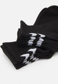 Calcetines negros apilados con una textura acanalada, que presentan patrones en zigzag blancos en el puño. El material parece suave y flexible.