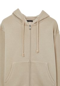 Felpa beige con zip realizzata in tessuto morbido. Presenta un cappuccio con cordini, tasche frontali e una texture liscia.
