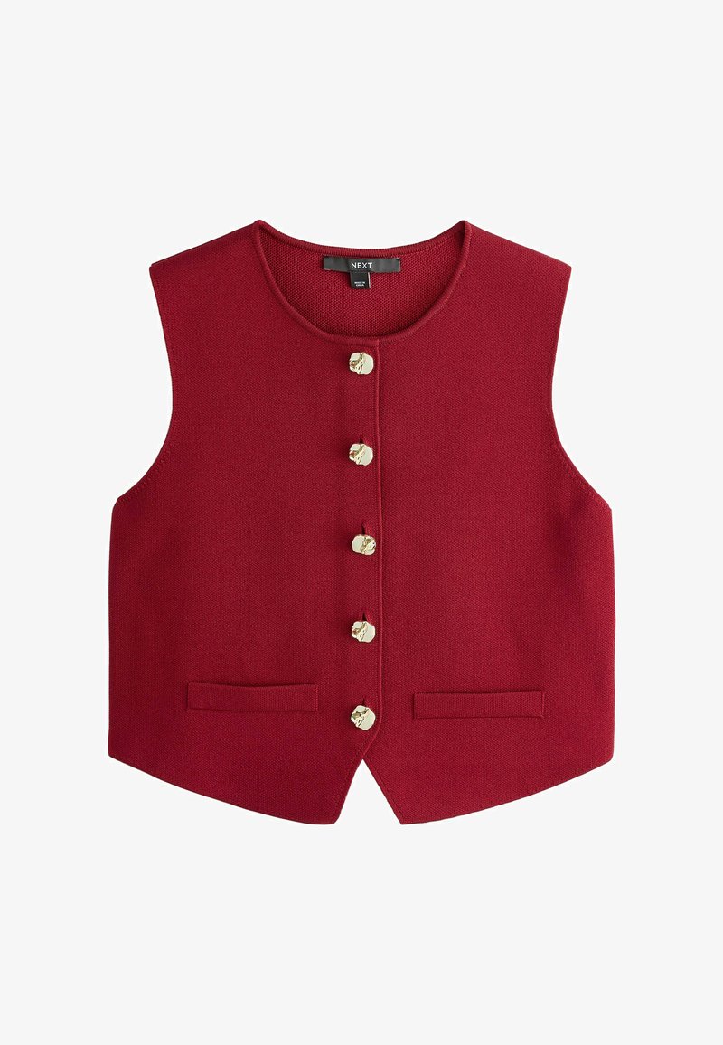 Sarkana adīta veste ar apaļu kakla izgriezumu, kuru rotā seši zelta krāsas pogas un divas priekšējās kabatas. Bez piedurknēm, gluda tekstūra.