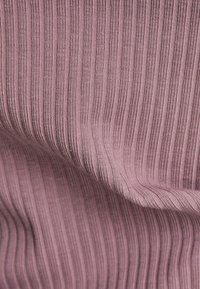 Textil i mjuk mauve med vertikala ränder. Tyget visar en ribbad textur med subtil lyster och fina sömnadsdetaljer genom hela.