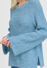 Maglione lavorato a maglia blu chiaro con una vestibilità ampia, maniche lunghe con polsini larghi e spacchi laterali per un comfort aggiuntivo. Motivo testurizzato in tutto il capo.