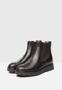 Stivali Chelsea in pelle marrone con finitura liscia, pannelli laterali in elastico e suola in gomma testurizzata per una presa e una durata elevate.