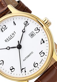 Gouden automatische horloge met witte wijzerplaat, zwarte cijfers en datumvenster. Bruine leren band en gestructureerde kroon. Made in Duitsland.