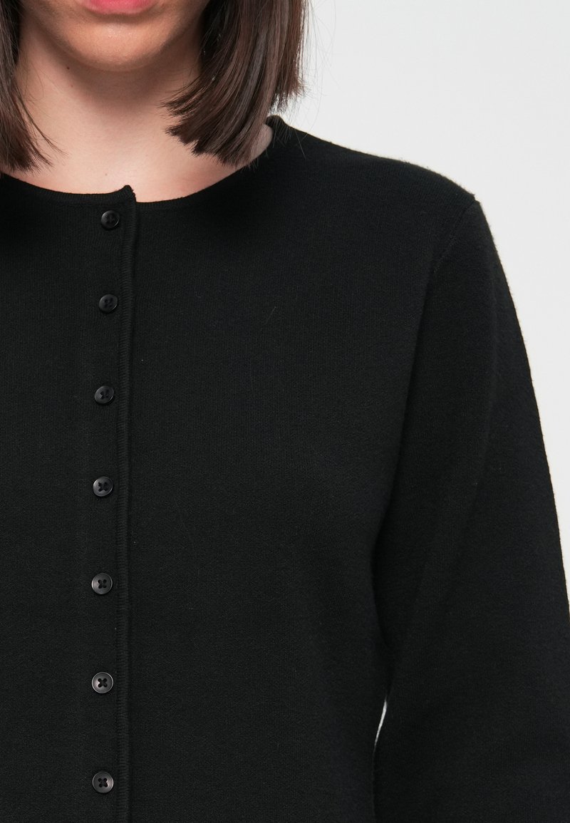 Czarny kardigan wykonany z miękkiego materiału, z okrągłym dekoltem i rzędem sześciu czarnych guzików z przodu. Prosty i klasyczny design.