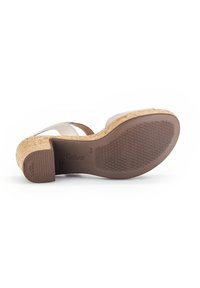 Sandaal met een bovenwerk van beige leer, een kurken wiggenhak en een gestructureerde rubberen zool. Heeft een kruisbandontwerp voor een veilige pasvorm.