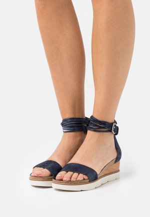 Marineblå ruskinds wedgesandaler med en bred tårem, ankelstrop og spænde. Med en struktureret korkplatform og hvid sål.