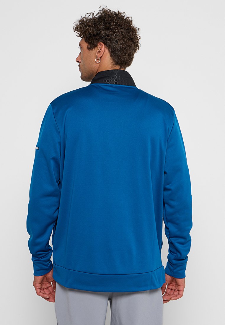 Pull bleu à manches longues avec un col noir texturé, fabriqué en tissu lisse, présentant une coupe décontractée et peu de détails sur les manches.
