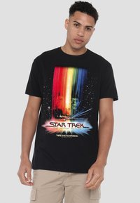 Black cotton t-shirt featuring a colorful "Star Trek: The Motion Picture" graphic with rainbow stripes and space-themed accents.